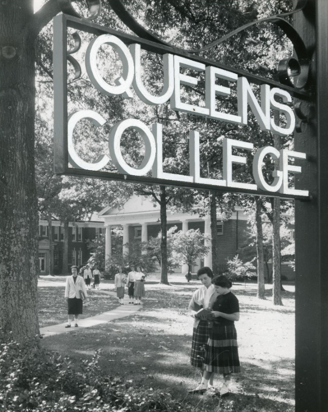 This image prominently features a large metal sign that says "QUEENS COLLEGE". Below the sign, groups of college students are shown walking around the campus quad.