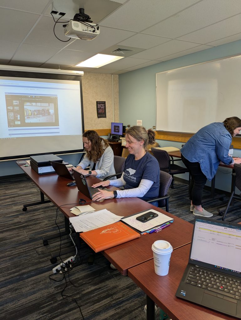 Two individuals sitting at a table working on their laptops.