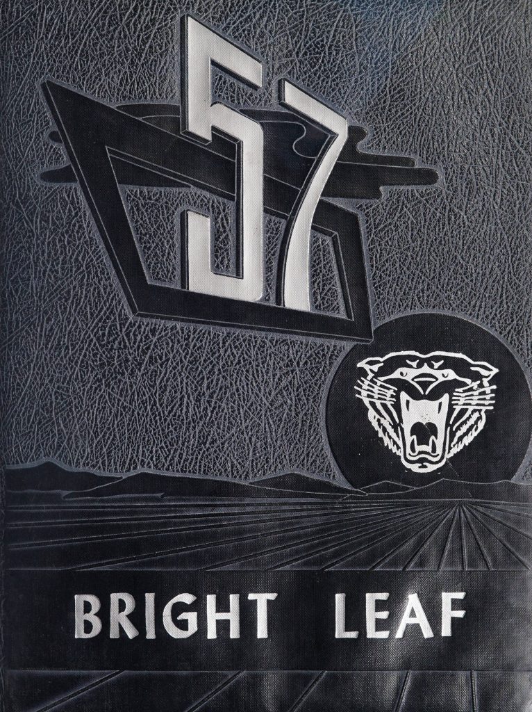The cover of the Bright Leaf [1957] that features long fields and gentle hills embossed onto the bottom half of the cover. A white illustration of a large cat with its mouth outstretched is located in the middle right area of the cover, and is diagonal to a large white embossed "57" that takes up much of the top half of the cover. The title "Bright Leaf" is printed in white towards the bottom.