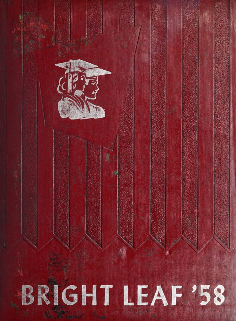 The cover of Bright Leaf [1958]. The red cover features embossed stripe detailing, an illustration of the bust of two graduates embossed in white, and the title "Bright Leaf '58" printed in white.