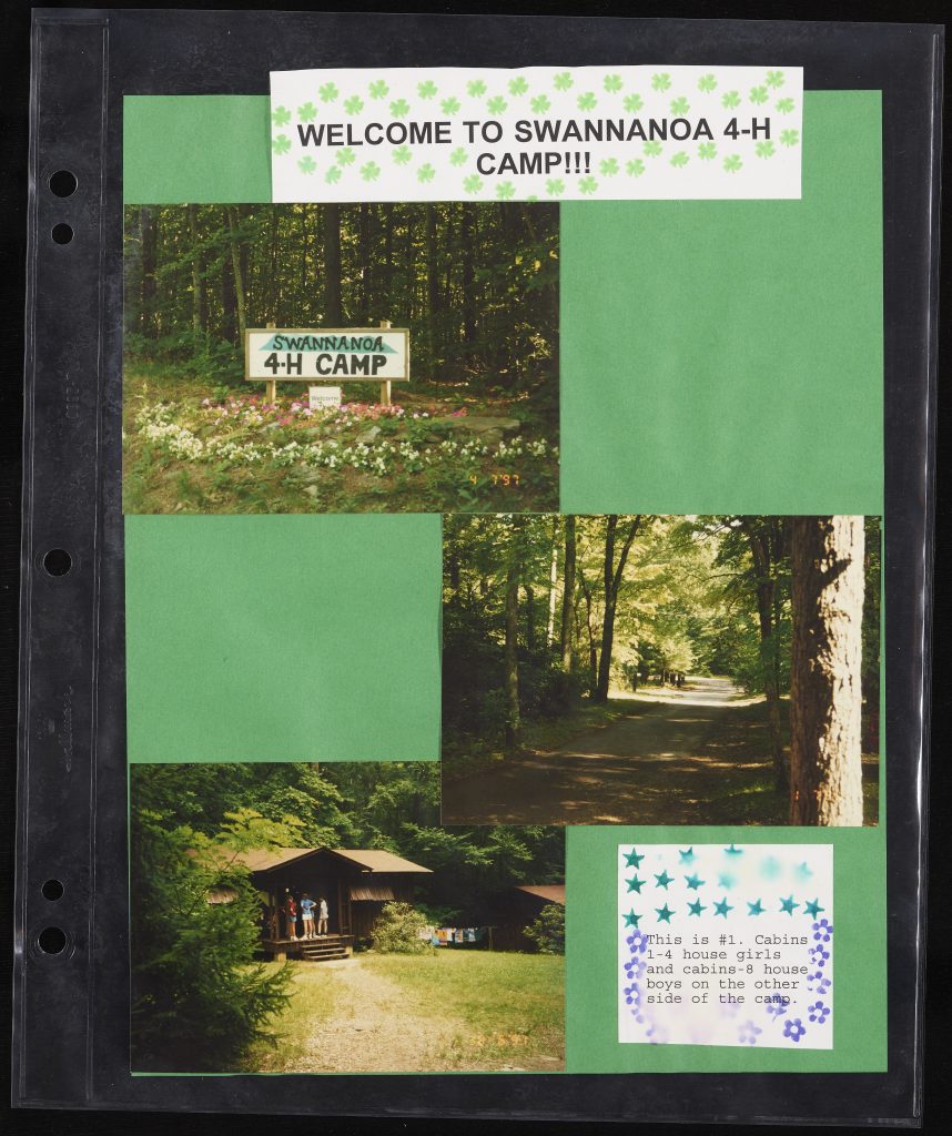 A green scrapbook page captioned "WELCOME TO SWANNANOA 4-H CAMP!!!'. Three color photographs are glued onto the page: one of the camp sign, another of a wooded trail, and another of a log cabin. A caption next to the third image reads "This is #1. Cabins 1-4 house girls and cabins-8 house boys on the other side of the camp."