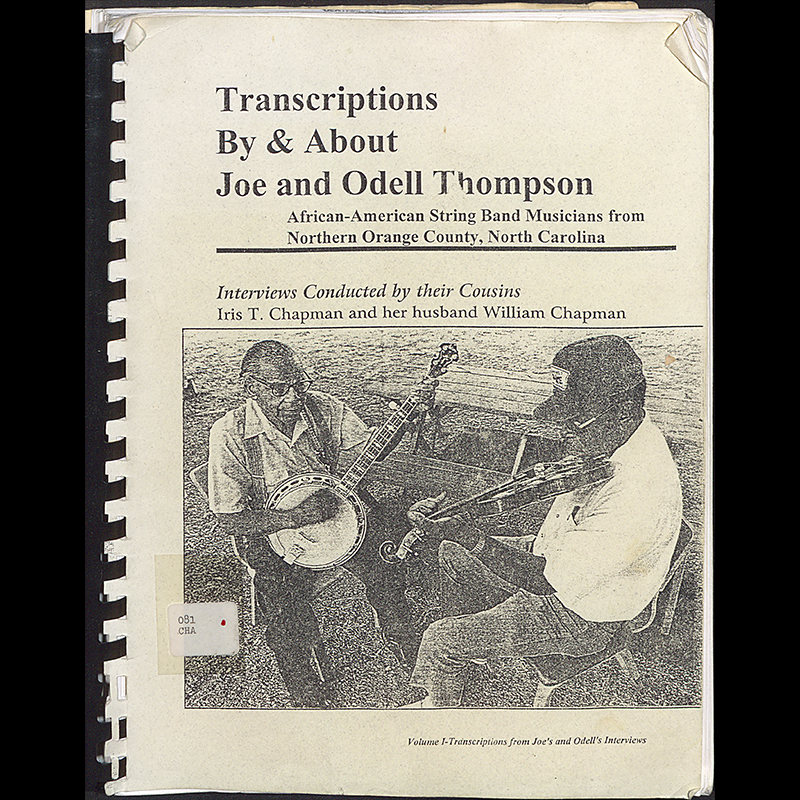 Cover page of a bound oral history transcript. Prominently on the cover is a picture of Joe and Odell Thompson; one is wearing a hat, button up short sleeved shirt, jeans, and glasses and is playing a fiddle and the other to the left is facing the camera wearing a button up short sleeved shirt, slacks, suspenders, and glasses and playing a banjo. They are both seated on chairs next to a picnic table outside.
