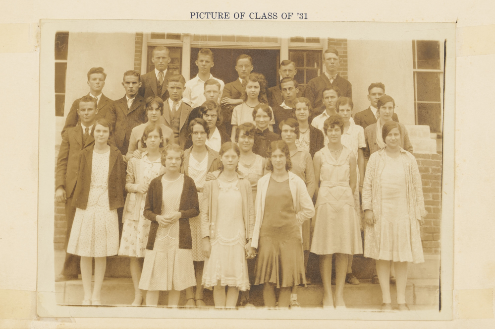 A group picture of the Class of '31 of Wendell High School. A co-ed group of about 30 students stand in several rows on the steps outside of a brick building.