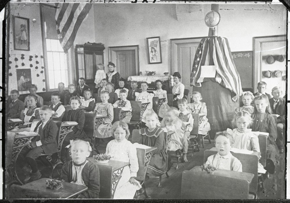 Group of school children and teachers sitting in desks in a classroom